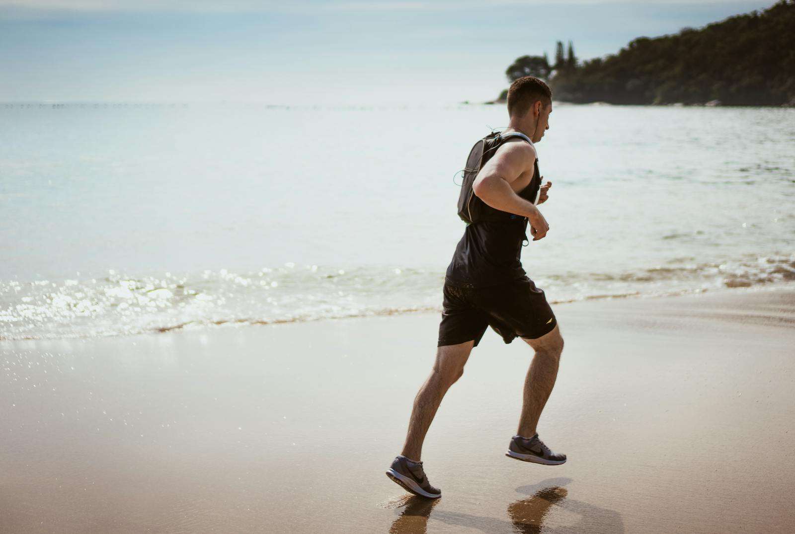 Man Wearing Black Tank Top and Running on Seashore