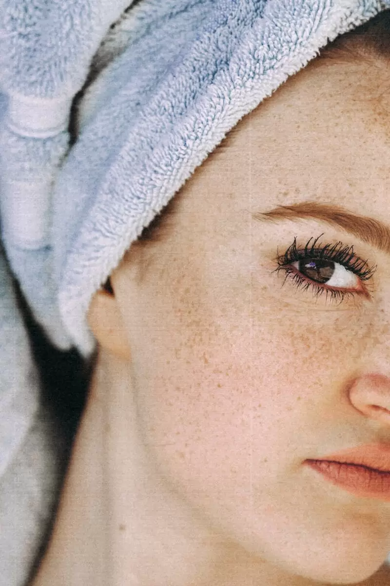 Young woman with brown eyes and freckled face and with towel turban on head looking at camera