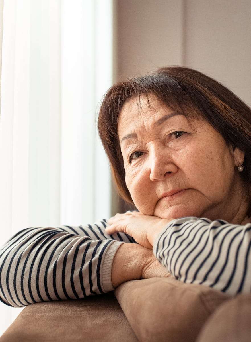 Mature Asian woman with wrinkles leaning on sofa