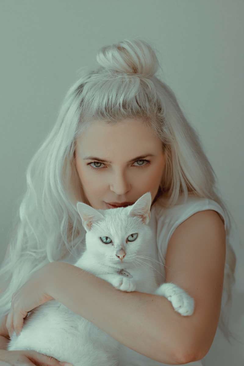 woman in white tank top with white cat on her lap