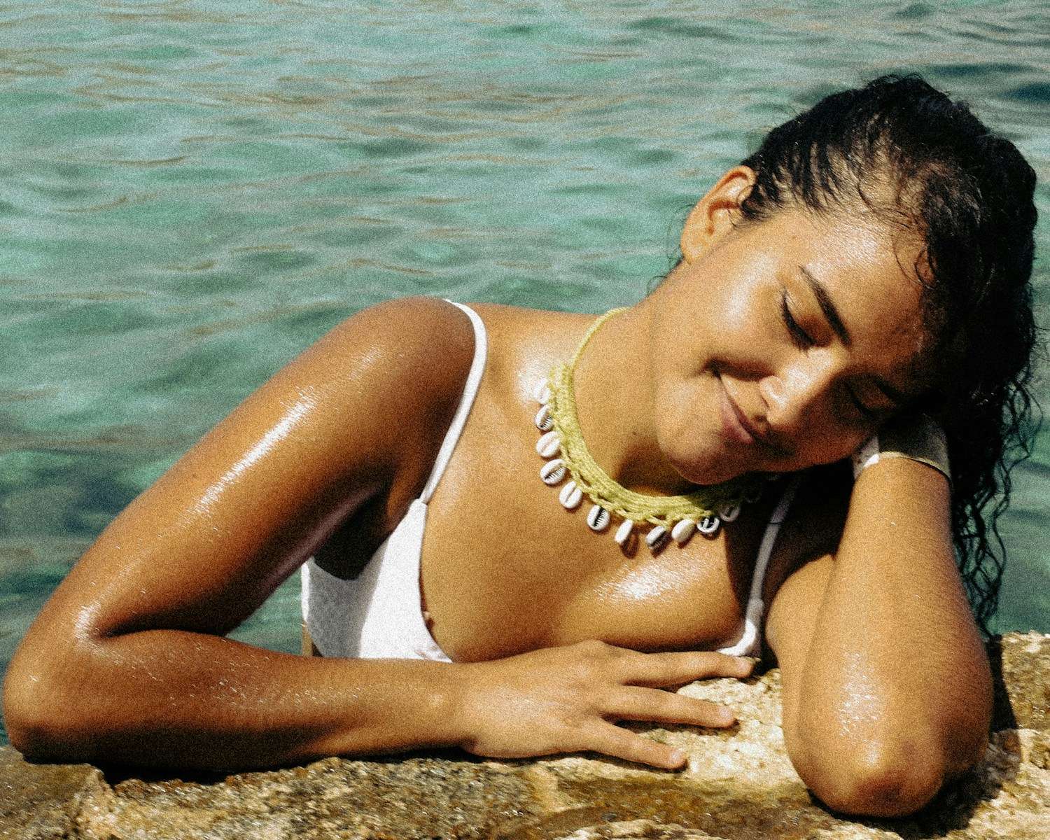 a woman laying on a rock next to a body of water